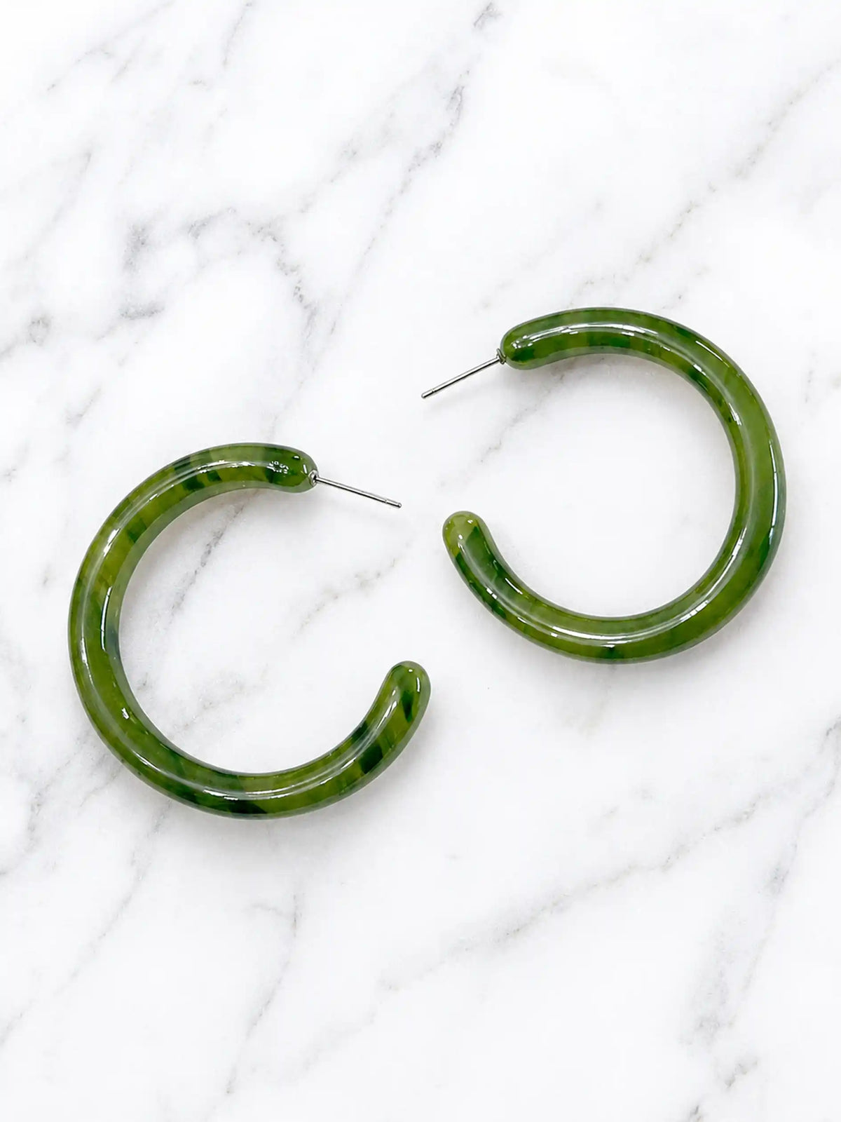 A pair of large, olive green toned hoop earrings made of mottled plastic.
