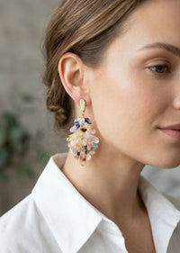 Close-up of a woman wearing colorful earrings with a neutral background