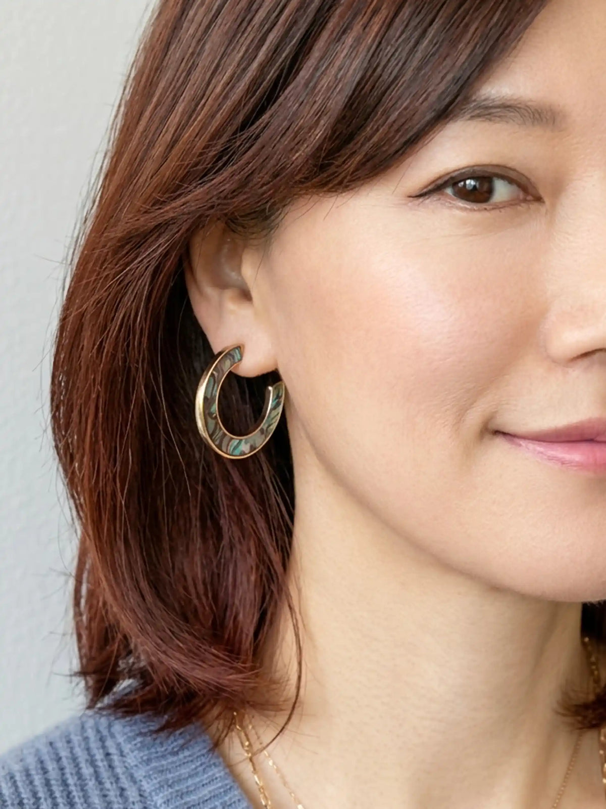 Natural abalone shell hoop earrings with iridescent blue, green, purple and black tones on gold hoops.