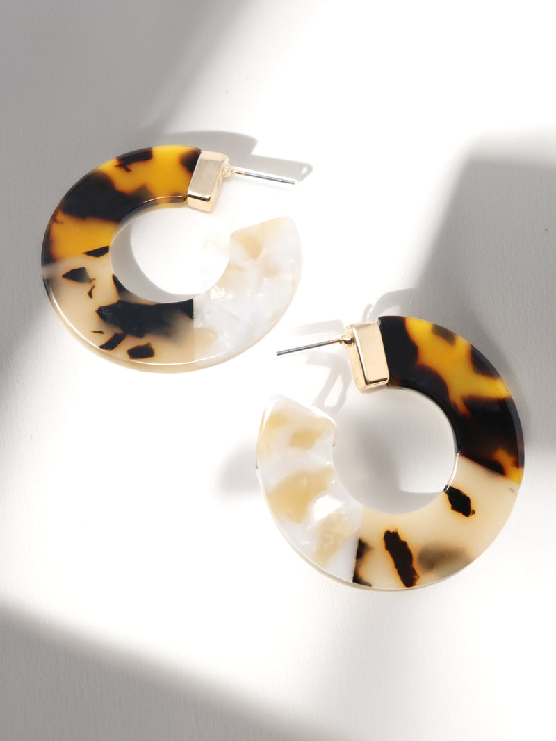 Tortoiseshell hoop earrings on a light gray background