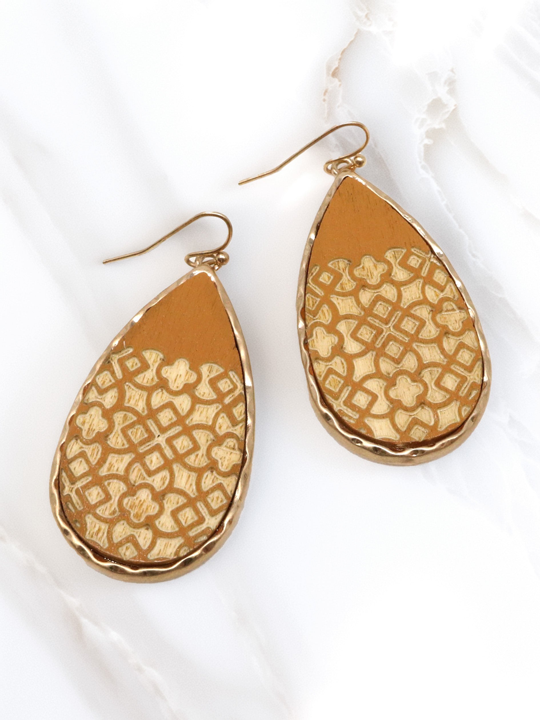 Gold teardrop earrings with intricate patterns on a white background