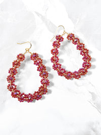 Pair of red beaded hoop earrings on a white background