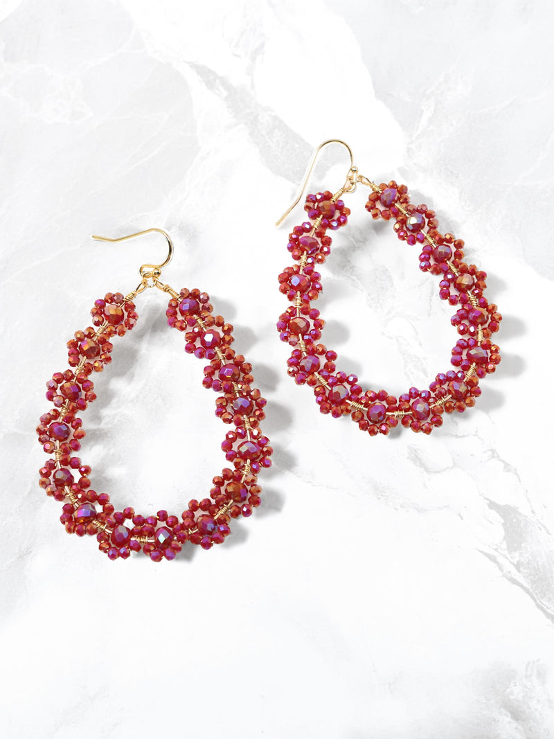 Pair of red beaded hoop earrings on a white background