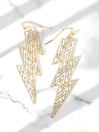 Gold lightning bolt earrings on a marble surface