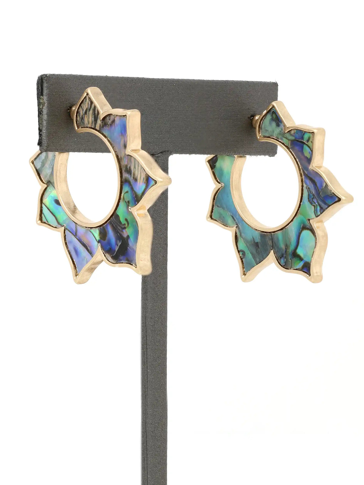 A pair of gold hoop earrings with scalloped abalone shell inlay, displayed on a black jewelry stand against a white background.