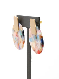 Colorful oval earrings on a black stand with a white background