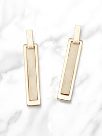 Gold bar earrings on a marble background