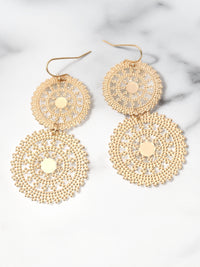 Gold circular earrings on a marble surface