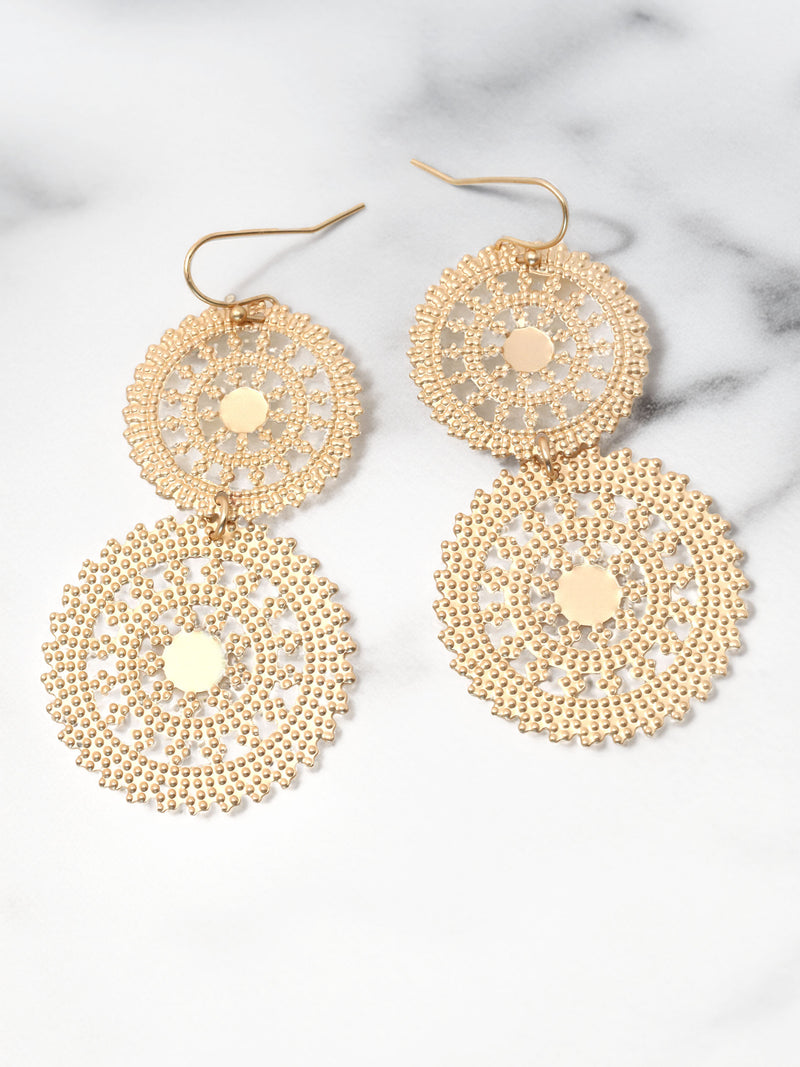 Gold circular earrings on a marble surface