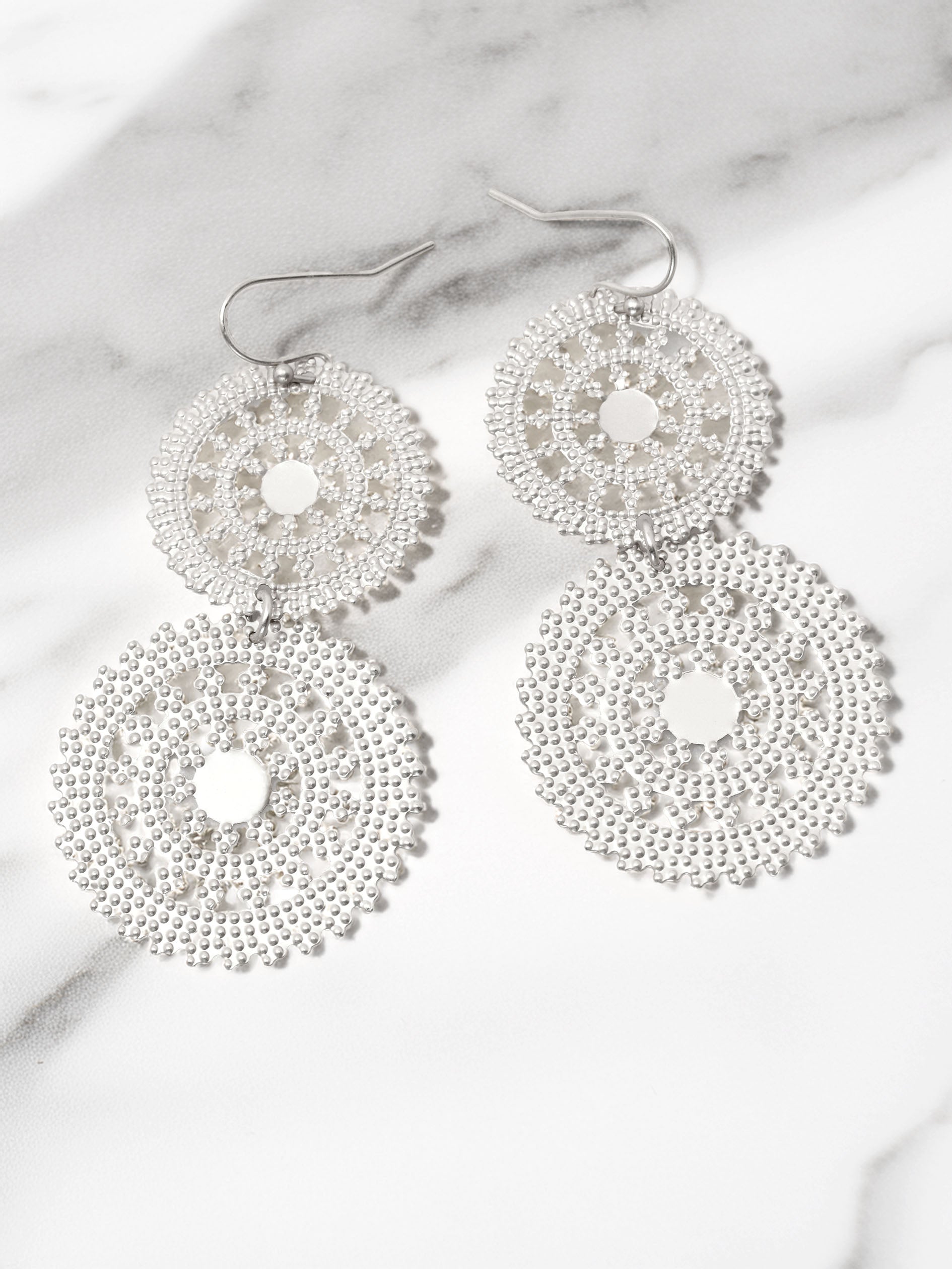 Silver beaded earrings on a marble surface