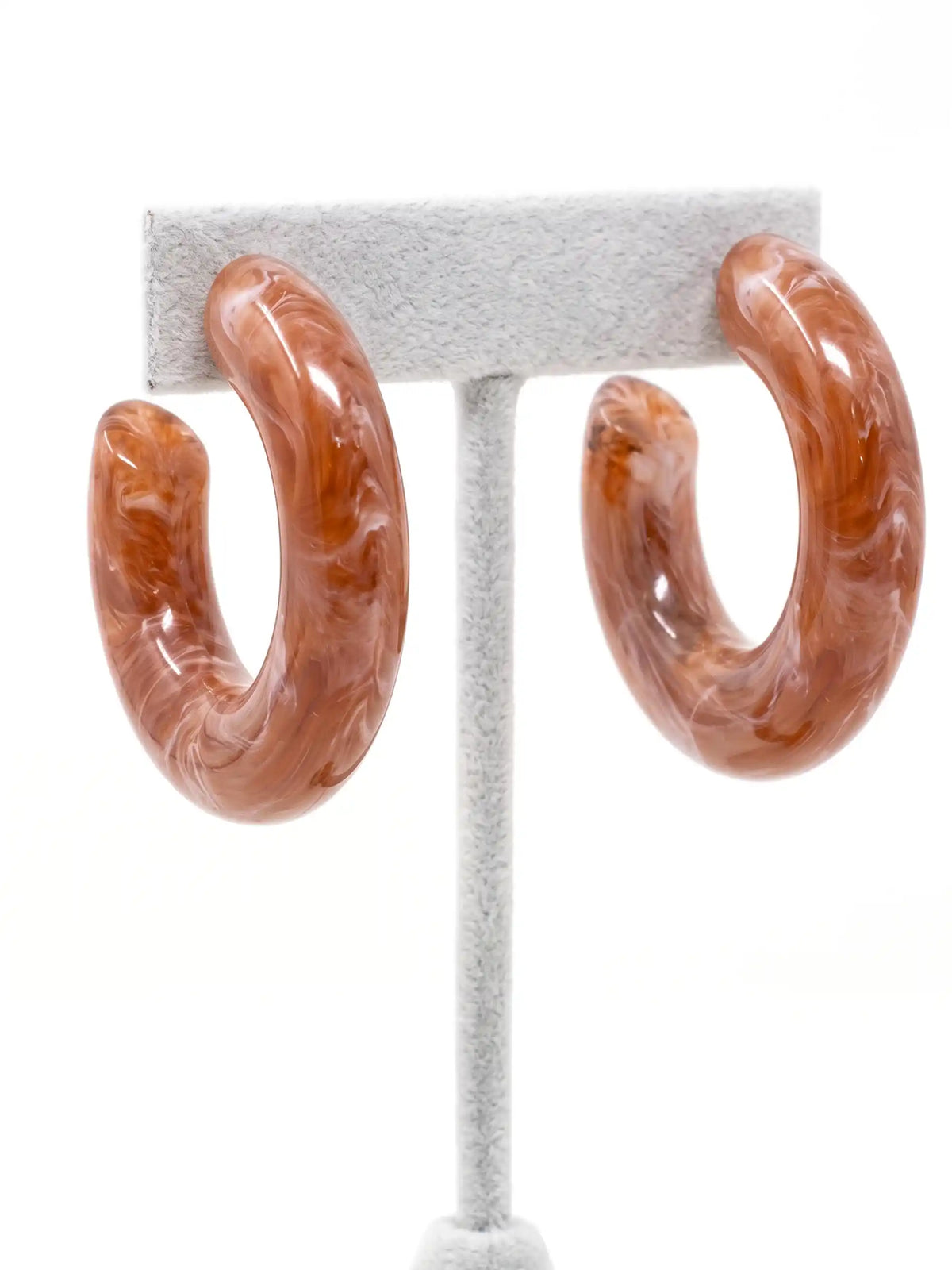 A pair of chunky, open C-shaped resin hoop earrings featuring a swirled brown and white marbled pattern.