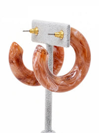 A pair of chunky, open C-shaped resin hoop earrings featuring a swirled brown and white marbled pattern.