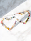 Two heart shaped hoop earrings with a white base and multi-colored swirls of red, pink, blue, yellow, green, and brown.