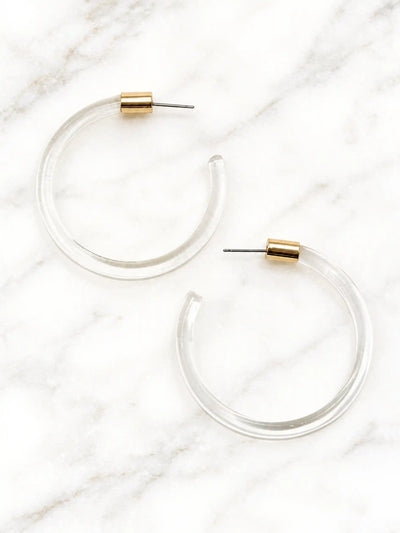 Pair of clear Lucite hoop earrings by Bauble Sky featuring polished transparent resin, gold-tone accents, and a modern minimalist design.