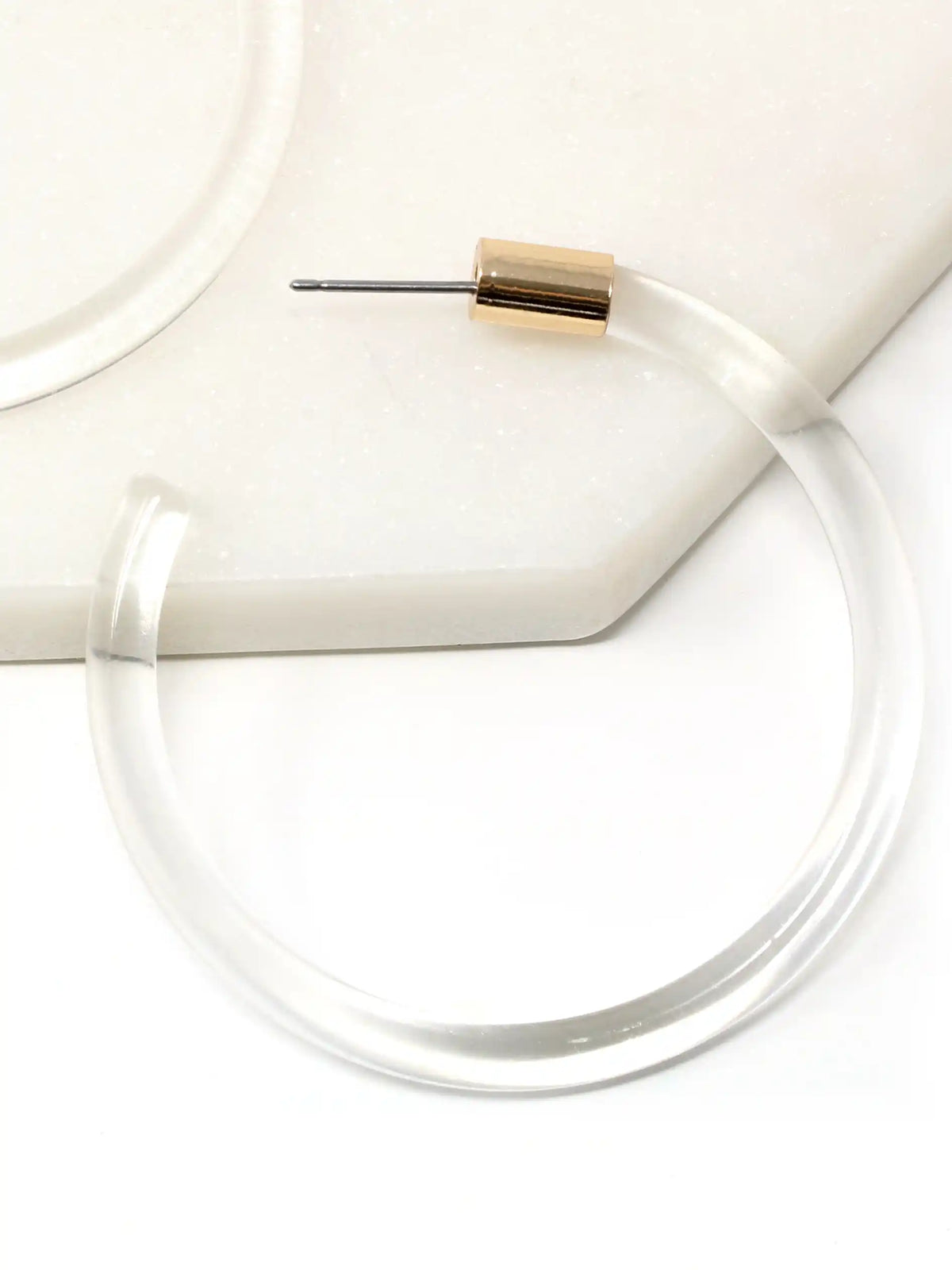 Pair of clear Lucite hoop earrings by Bauble Sky featuring polished transparent resin, gold-tone accents, and a modern minimalist design.