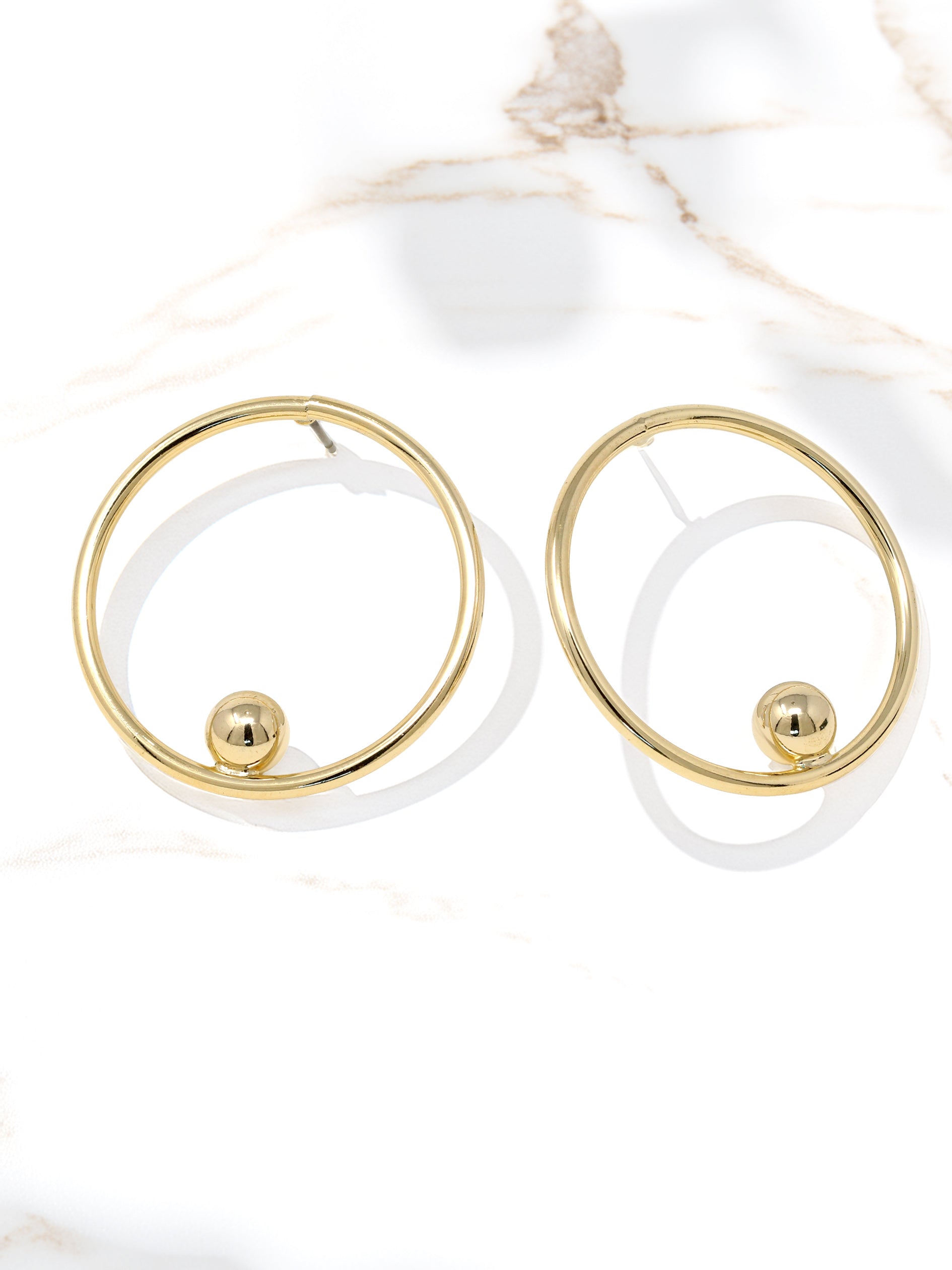 Gold hoop earrings with a central sphere on a white background