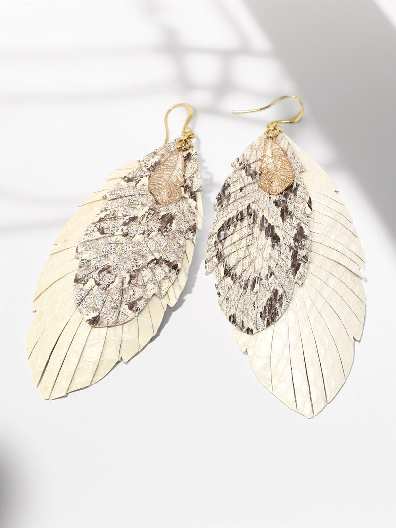 Pair of leaf-shaped earrings with gold and silver details on a light background