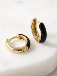 A pair of small gold-plated huggie hoop earrings featuring contrasting colorful black epoxy accents in a modern, compact design.