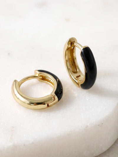A pair of small gold-plated huggie hoop earrings featuring contrasting colorful black epoxy accents in a modern, compact design.