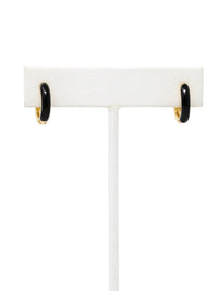 A pair of small gold-plated huggie hoop earrings featuring contrasting colorful black epoxy accents in a modern, compact design.