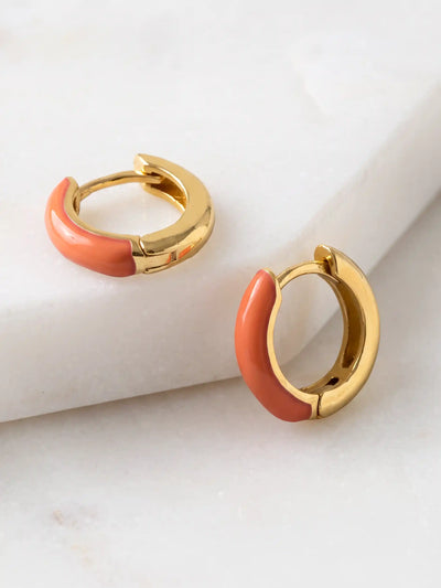 A pair of small gold-plated huggie hoop earrings featuring contrasting colorful orange epoxy accents in a modern, compact design.