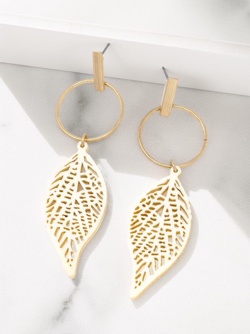Gold leaf-shaped earrings on a white surface