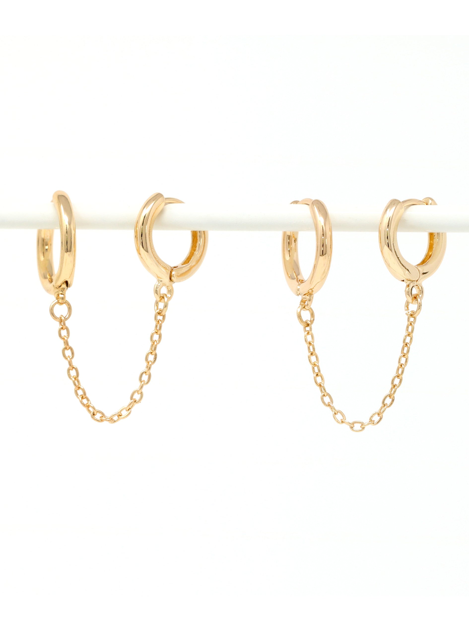 Gold hoop earrings with chains on a white background