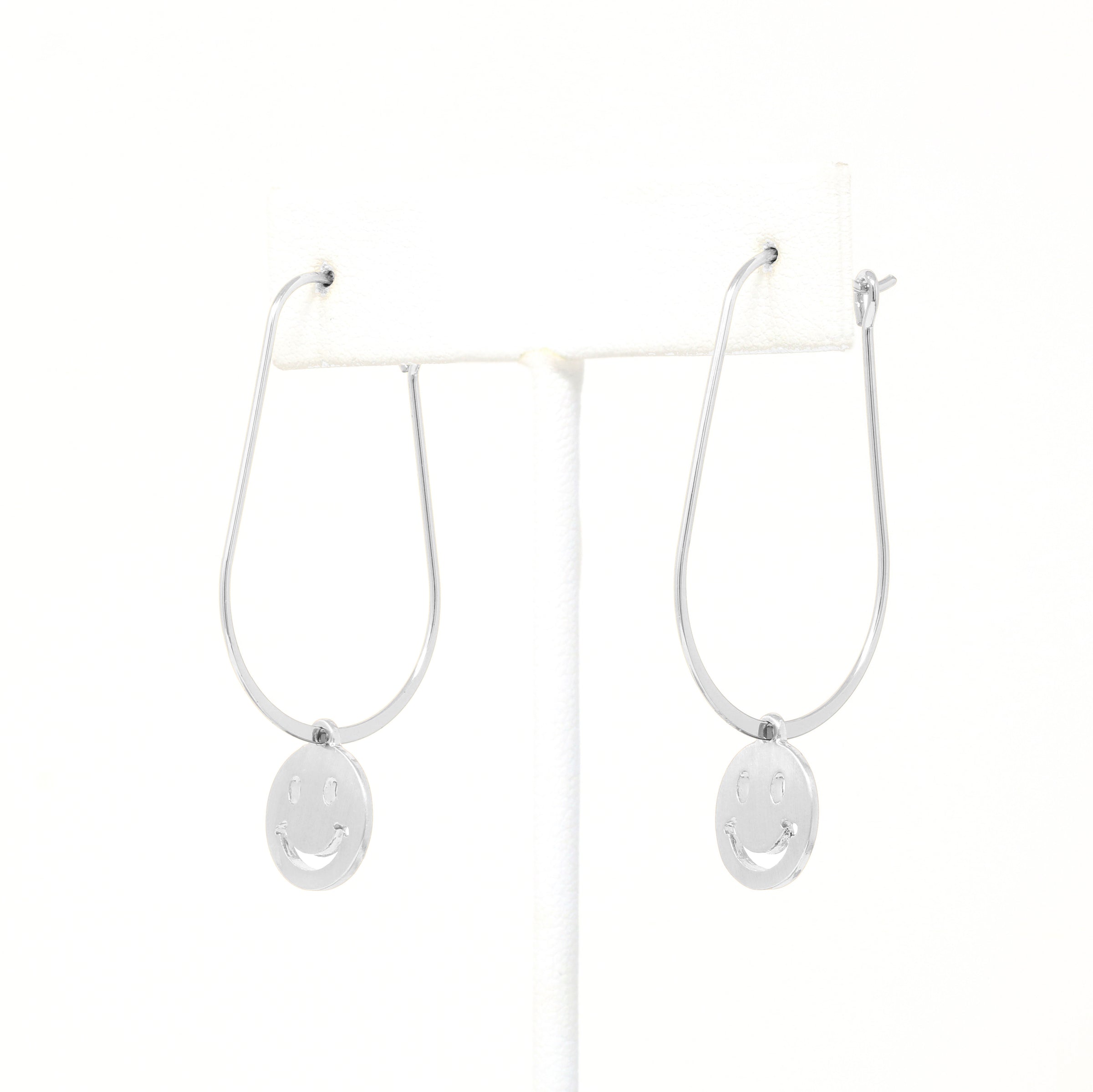 A pair of smiley face charmed teardrop hoop earrings in silver.
