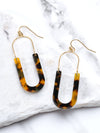 A pair of oval resin drop and dangle earrings with gold-tone hooks and frames. The U-shaped resin pendants feature a brown tortoise tones.