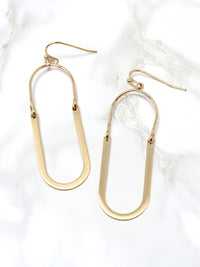 Oval shaped earrings featuring metal drops suspended from gold-plated hooks.