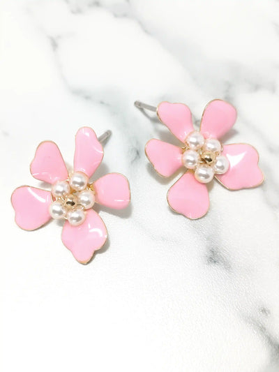 Pink flower-shaped earrings with pearl centers on a marble surface