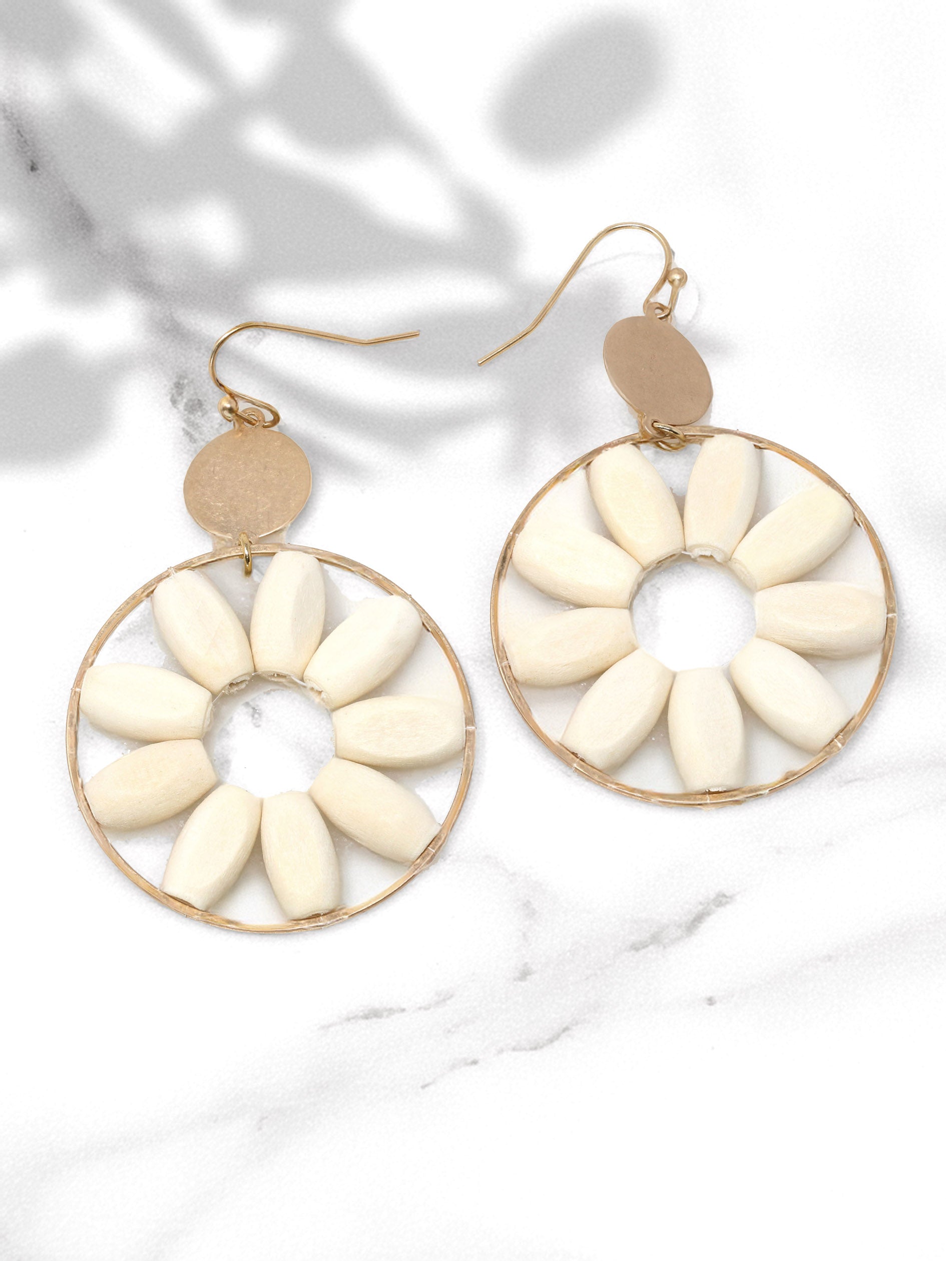 Pair of earrings with white circular designs on a light background