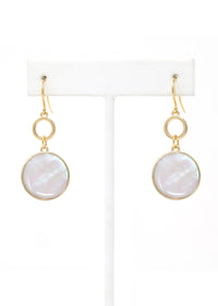 Gold earrings with round white stones on a white stand