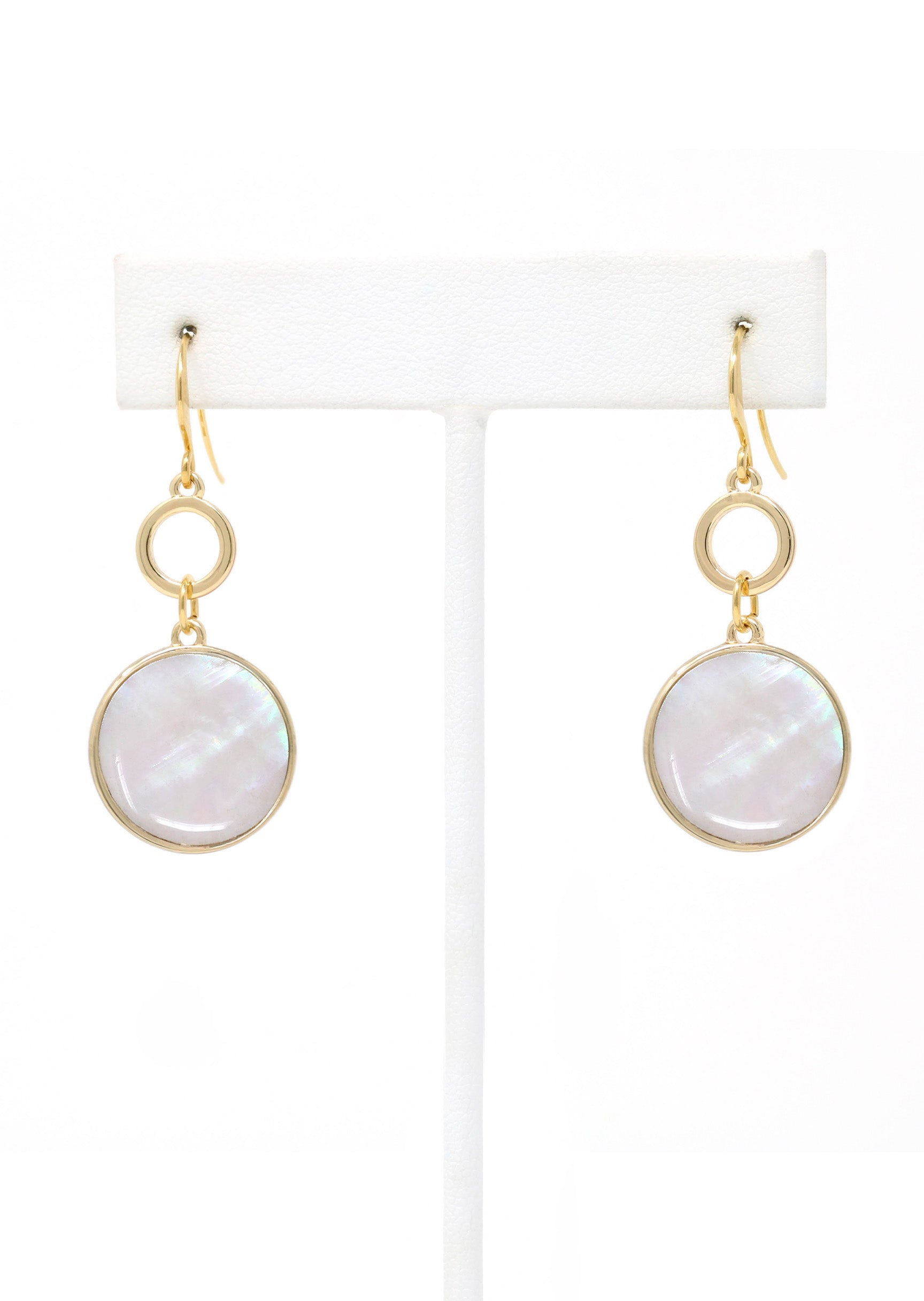 Gold earrings with round white stones on a white stand