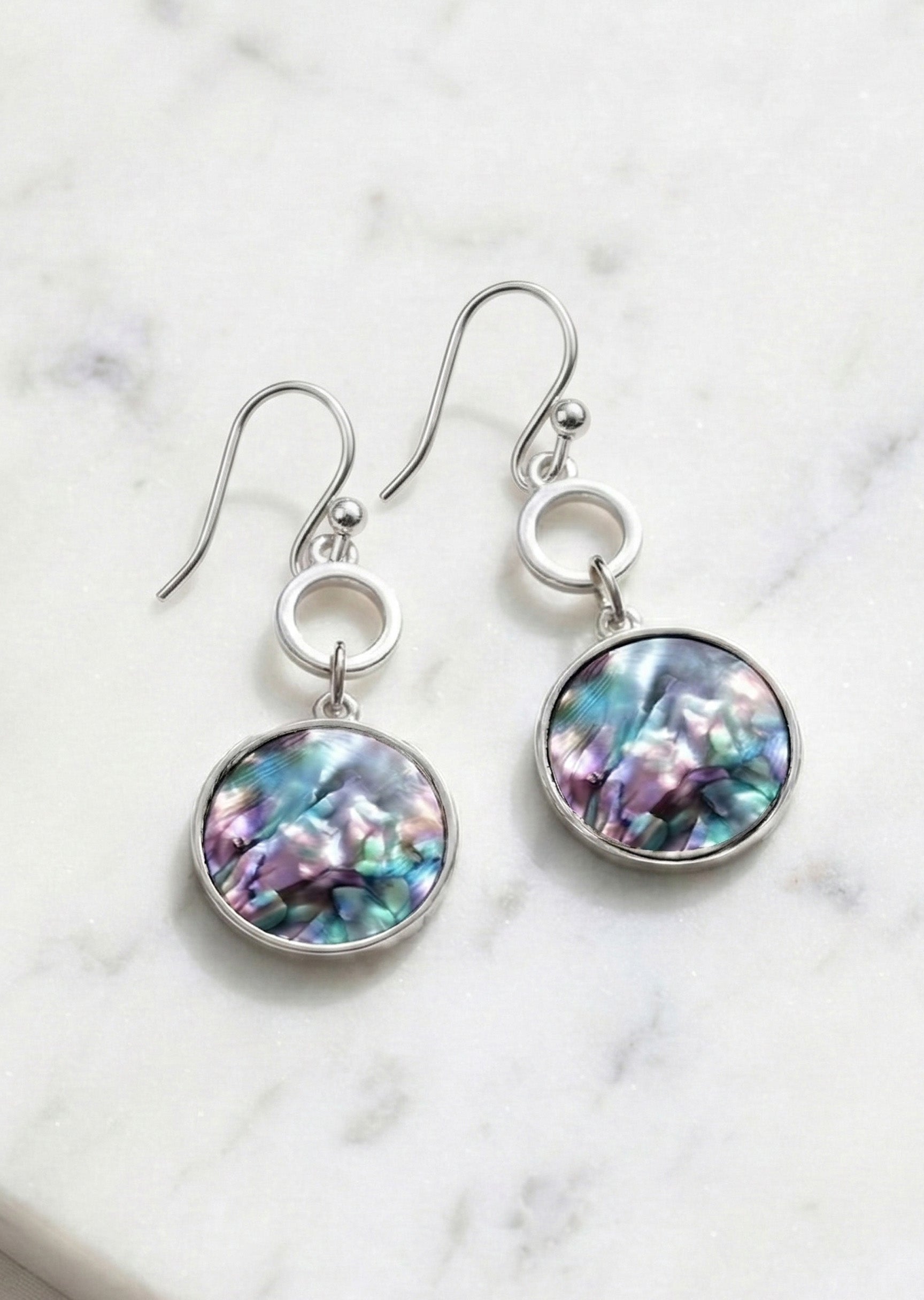 Pair of earrings with colorful round stones on a marble background