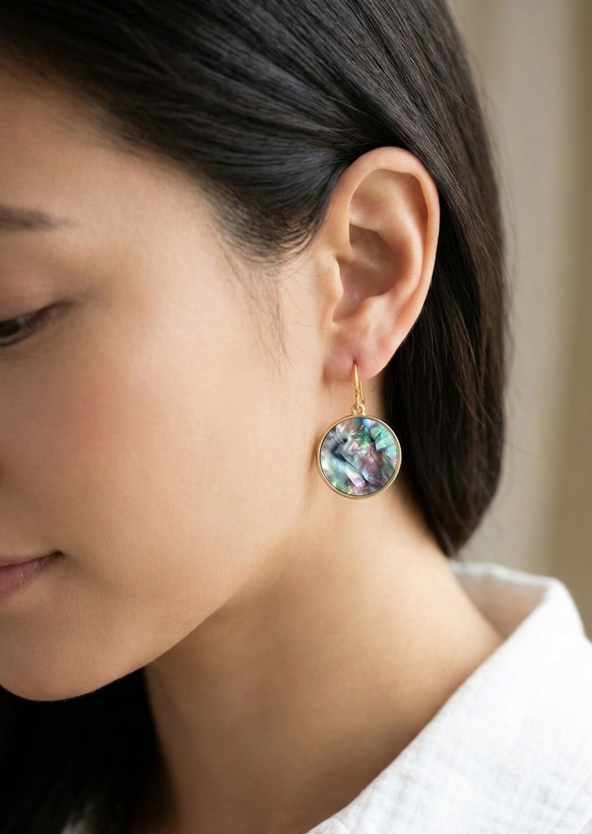 Close-up of a woman wearing a round earring with a colorful design.