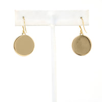 Gold round earrings on a white earring stand