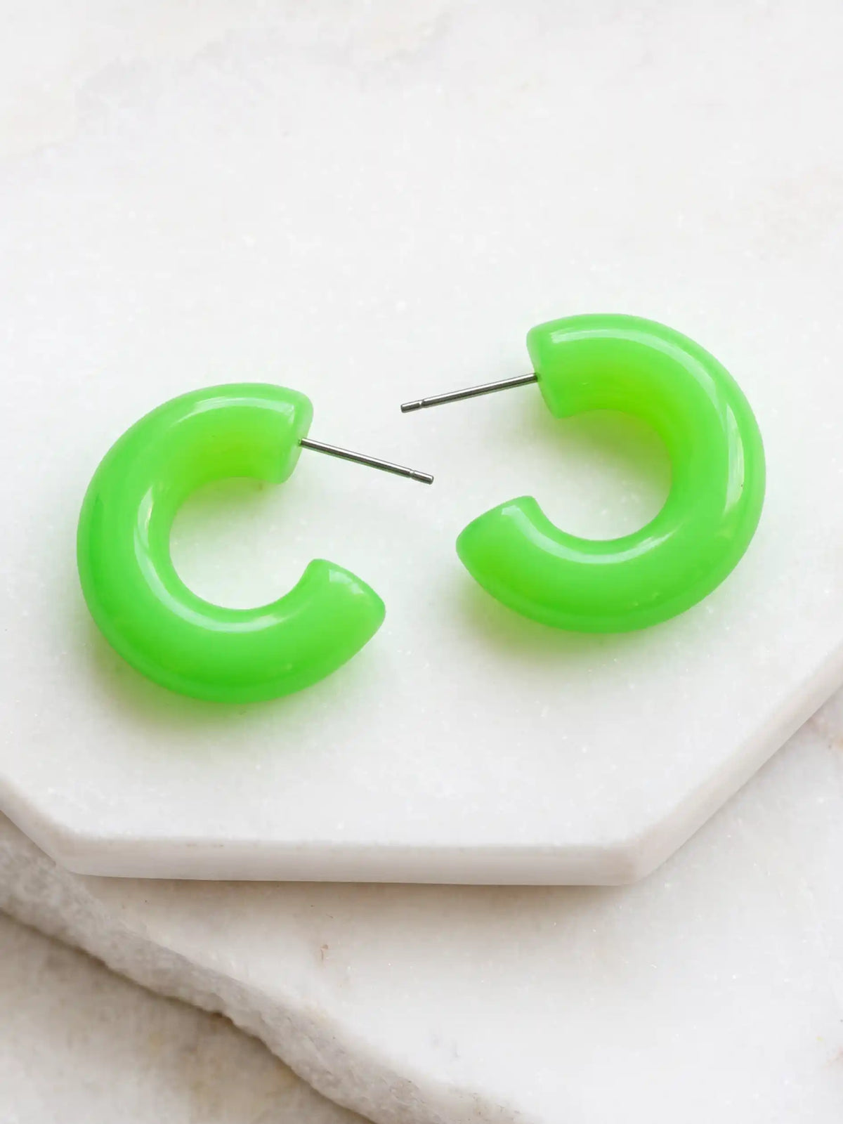 A pair of neon green colored resin hoop earrings with a bold rounded 25mm design.
