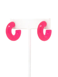 A pair of neon pink colored resin hoop earrings with a bold rounded 25mm design.