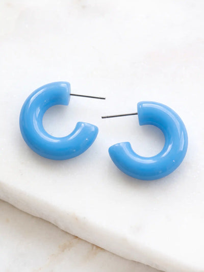 A pair of tranquil blue colored resin hoop earrings with a bold rounded 25mm design.