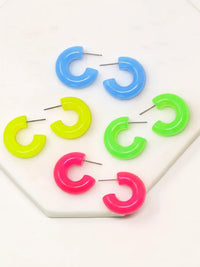 Pair of neon colored resin hoop earrings with a bold rounded 25mm design, available in vibrant pink, yellow, green, and tranquil blue, by Bauble Sky.