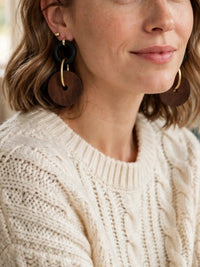 Woman wearing brown wooden circle drop earrings.