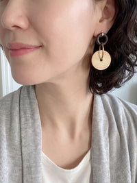 Woman wearing ivory wooden circle drop earrings.