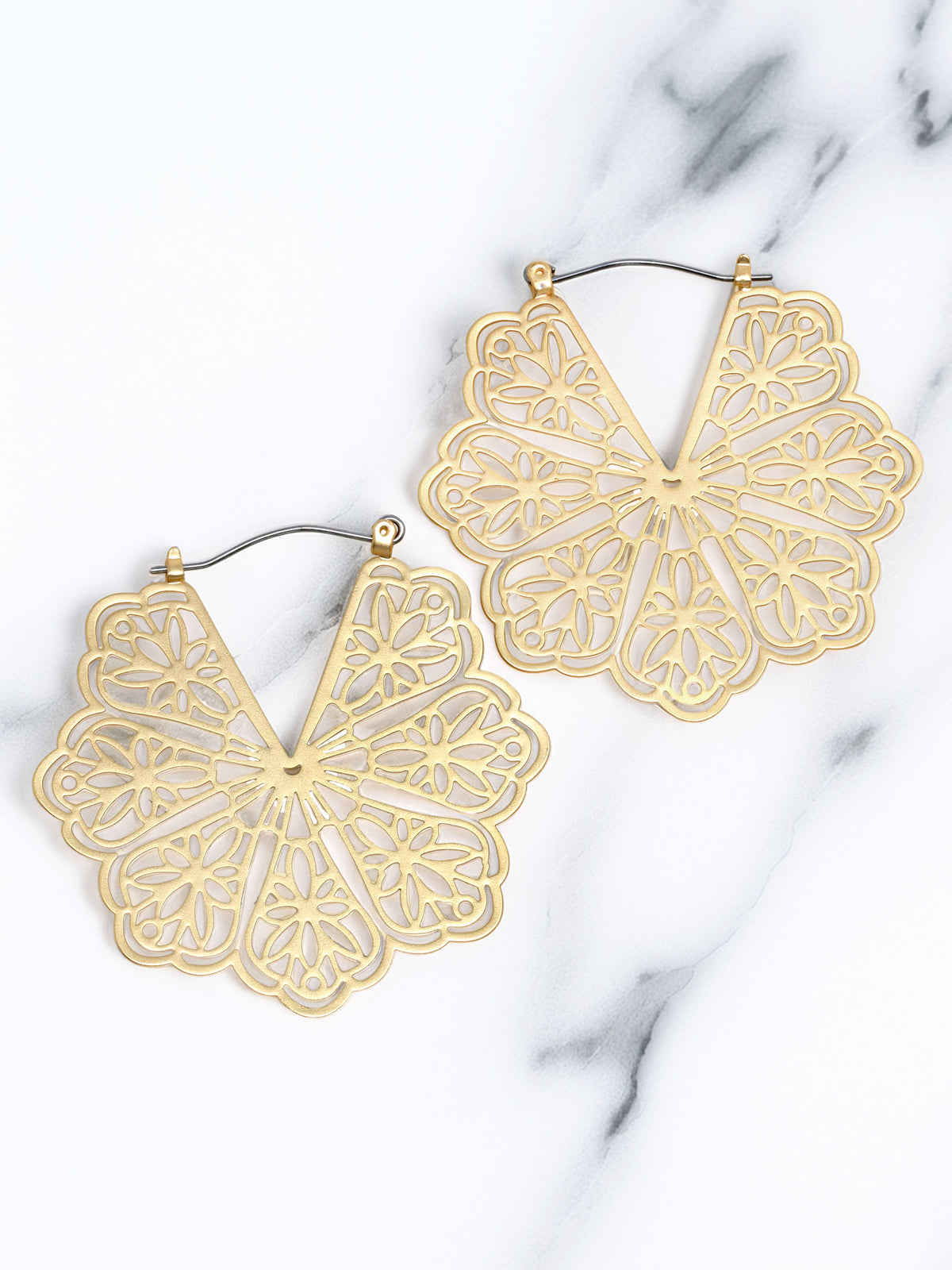 Gold flower-shaped earrings on a marble surface