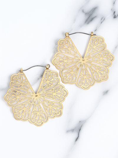 Gold flower-shaped earrings on a marble surface