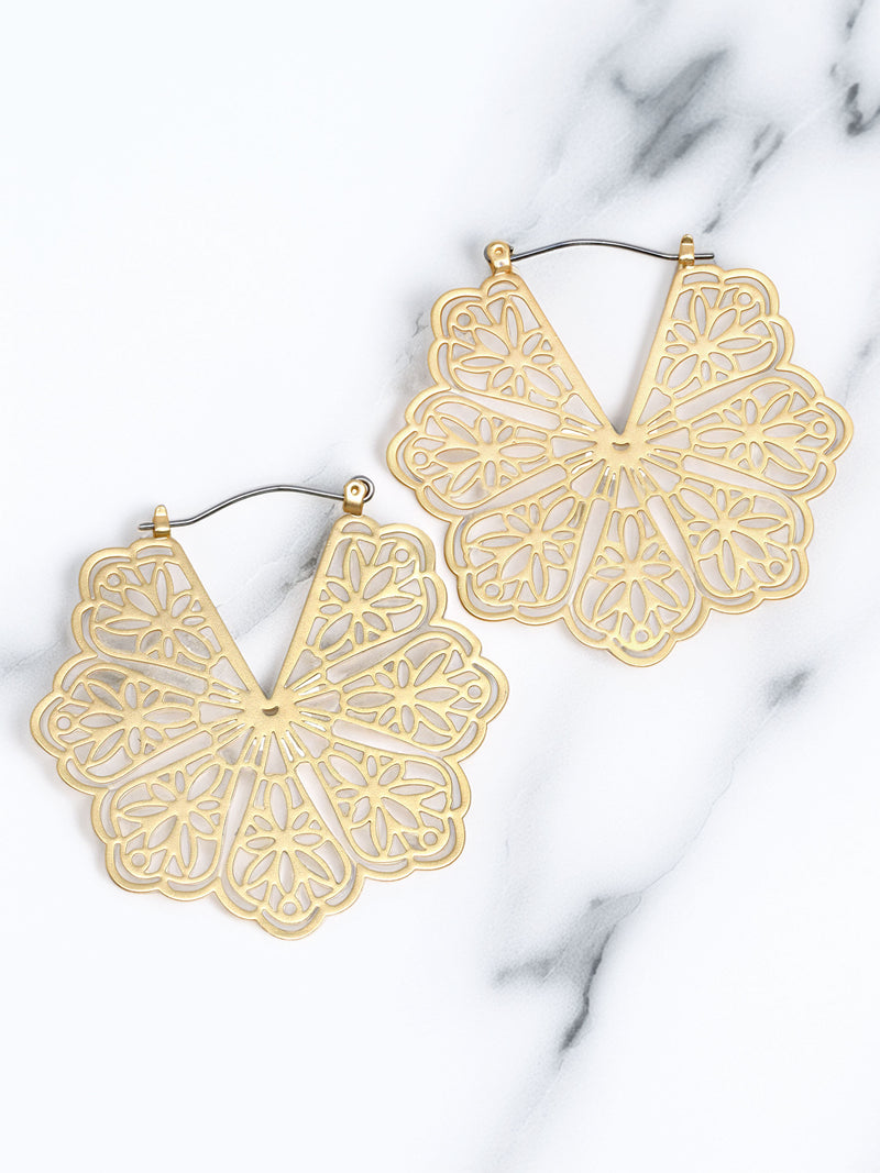 Gold flower-shaped earrings on a marble surface