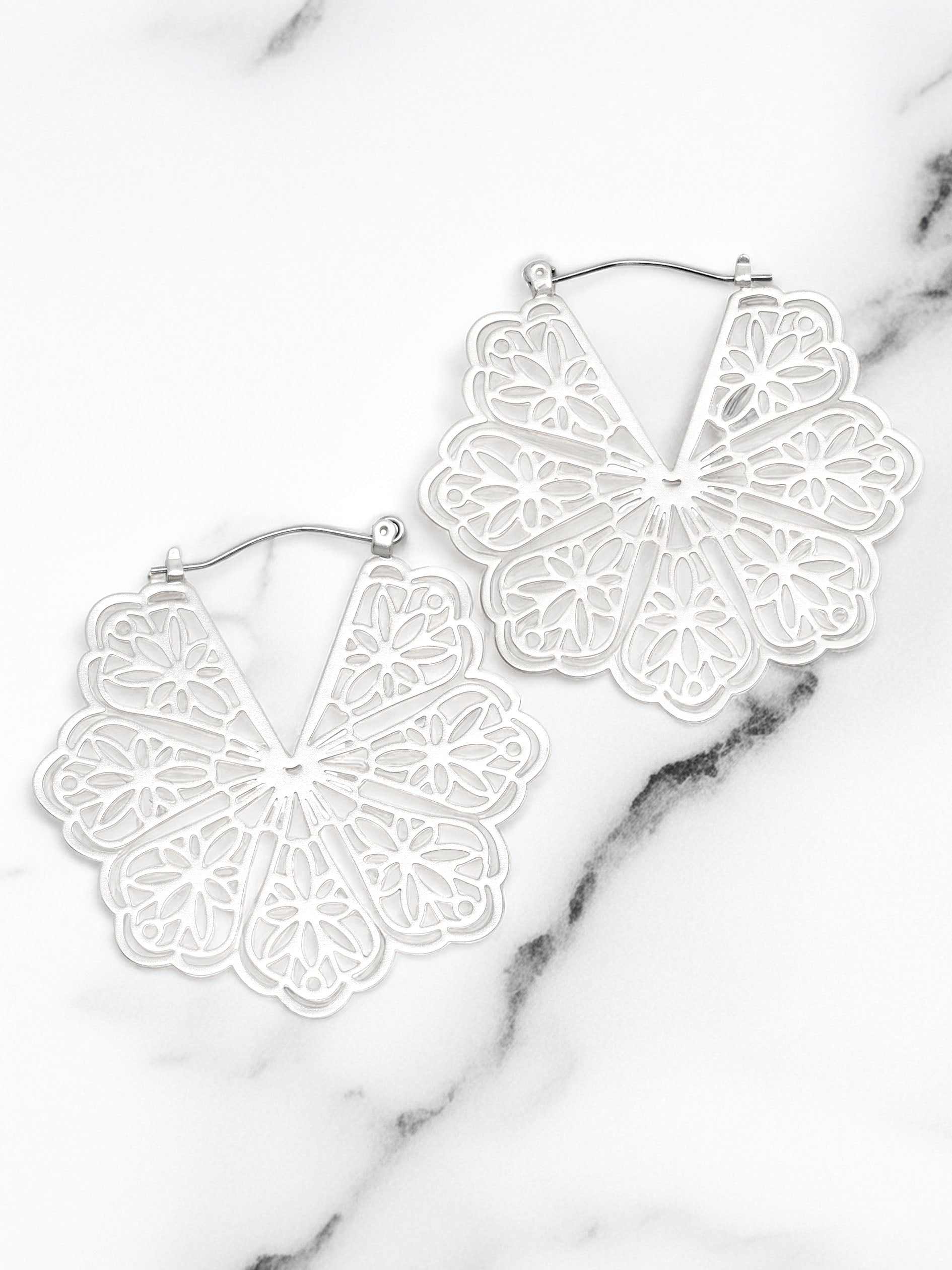 White lace-style earrings on a marble surface