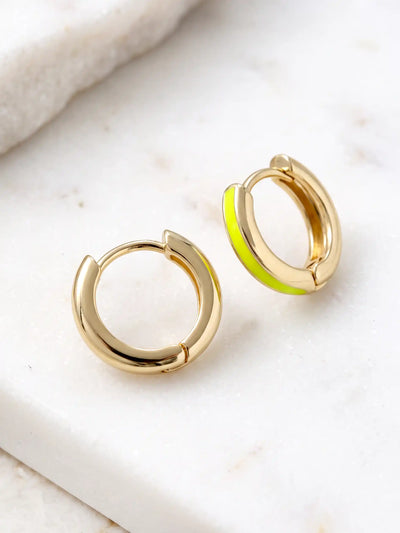 A close-up of a pair of 15mm gold-plated huggie hoop earrings with a  neon yellow epoxy color accent on one side.