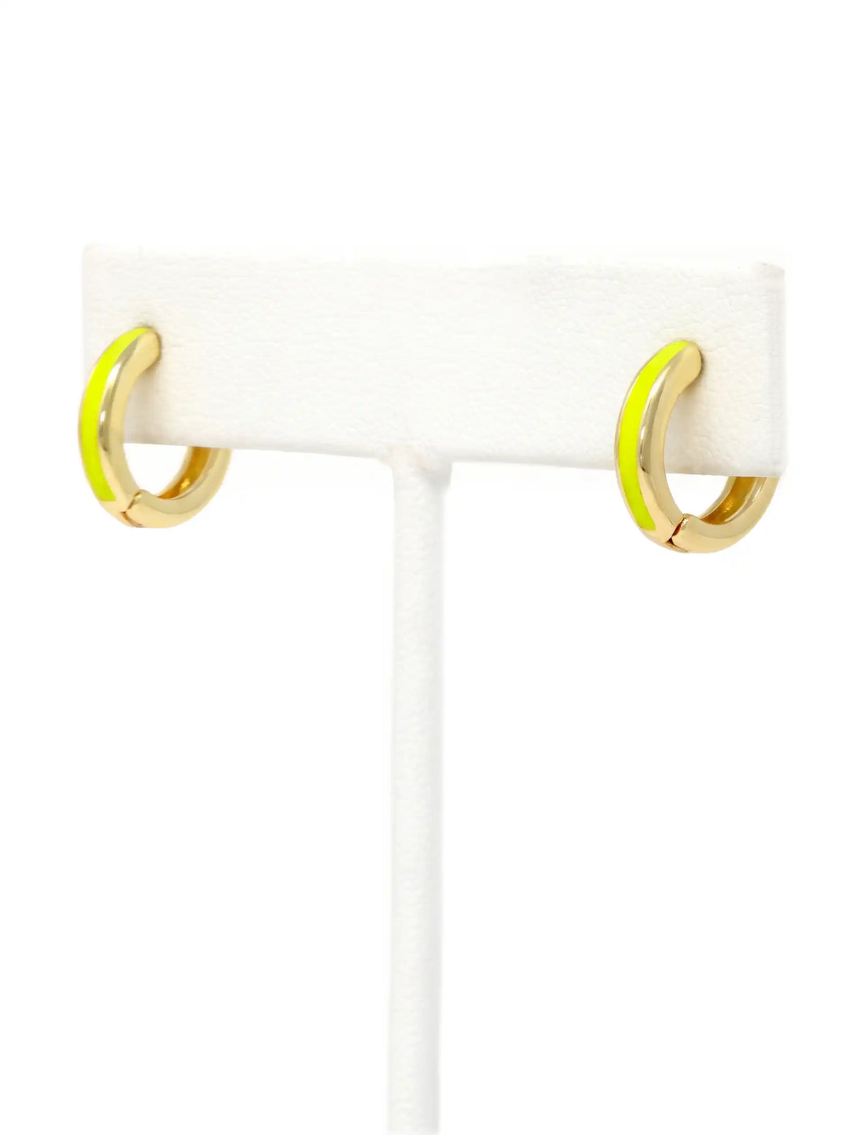 A close-up of a pair of 15mm gold-plated huggie hoop earrings with a  neon yellow epoxy color accent on one side.