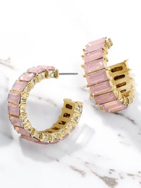 Pink hoop earrings with gold accents on a marble surface